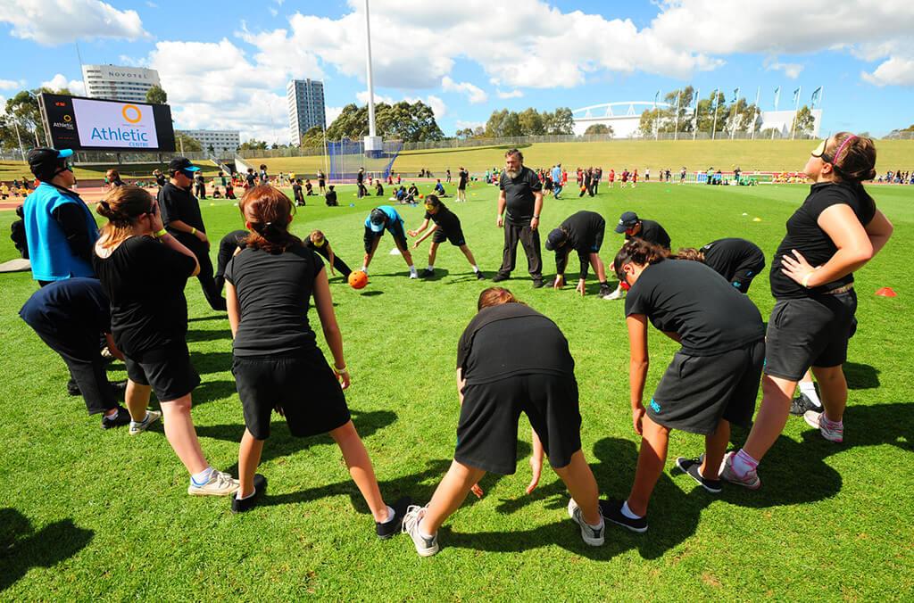 People on a green grass field passing a ball at the Athletic Centre