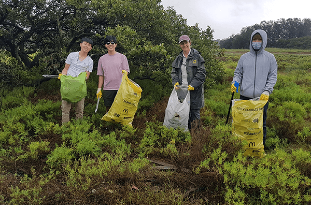 Park ranger with three volunteers, with cleaning equipment, in the Park