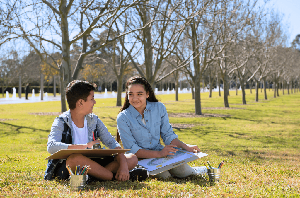 Two children sitting and drawing in a park at Sydney Olympic Park