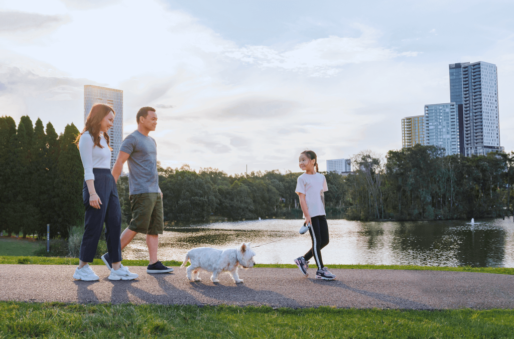 Family walking a dog along a park in Sydney Olympic Park